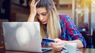 Sad woman with her hand on her head and holding a credit card.