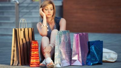 Sad shopper on the ground with shopping bags.