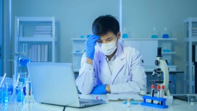 A sad looking scientist sitting and upset about a share price fall.