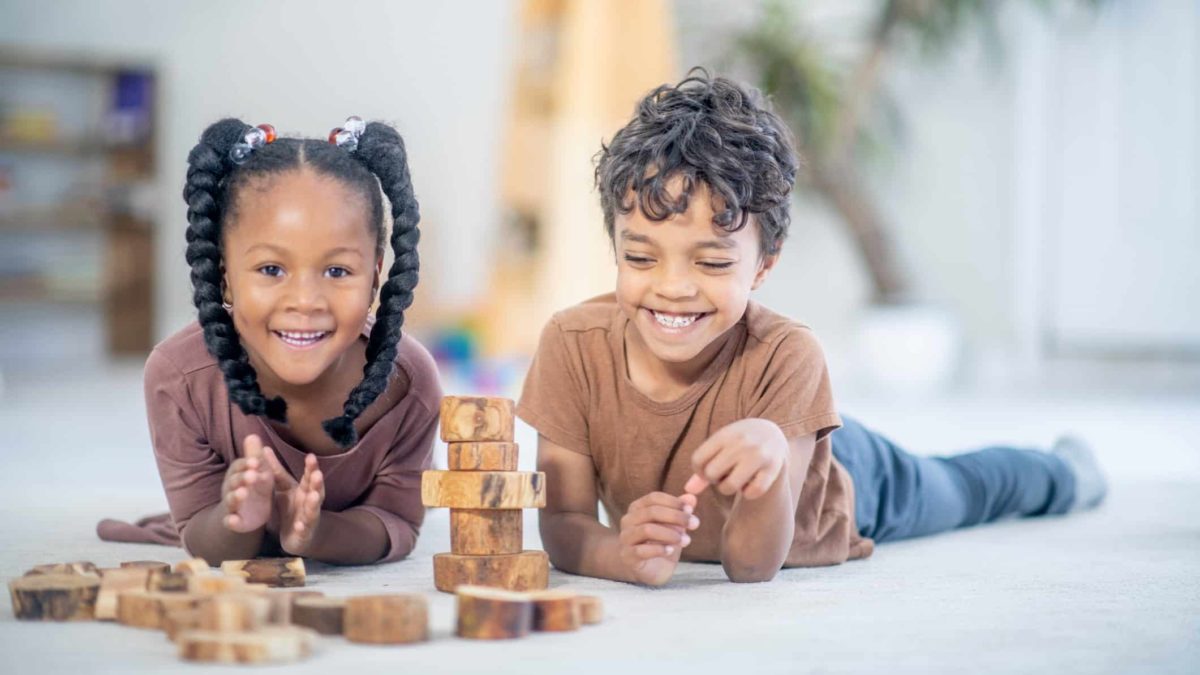 Two kids playing with wooden blocks, symbolising small cap shares and short selling.