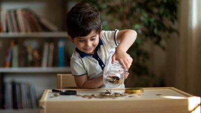 Kid pouring out coins from the money jar.