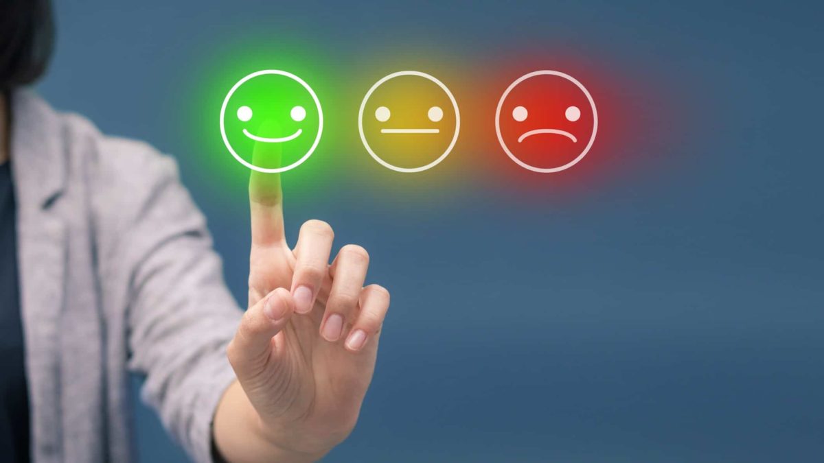 Happy, neutral and sad smiley faces with a finger pointing at the smiling emoji.