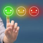 Happy, neutral and sad smiley faces with a finger pointing at the smiling emoji.