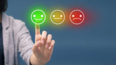 Happy, neutral and sad smiley faces with a finger pointing at the smiling emoji.