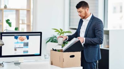 A man packs up a box of belongings at his desk as he prepares to leave the office.