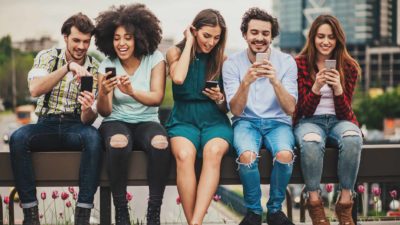 Five happy friends on their phones.