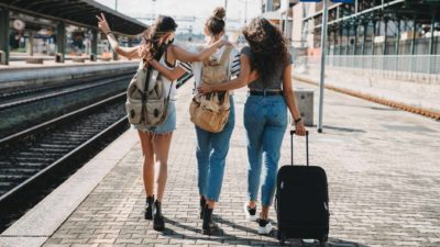 Three friends walking together at a train station.