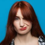 A woman looks unimpressed on a blue background.