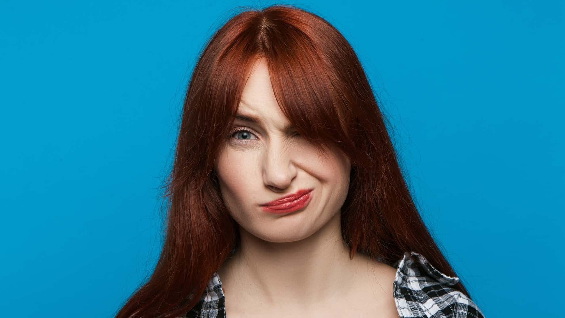 A woman looks unimpressed on a blue background.
