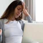 Upset woman with her hand on her forehead, holding a credit card.