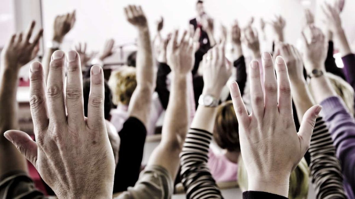 People raise their hands to vote.