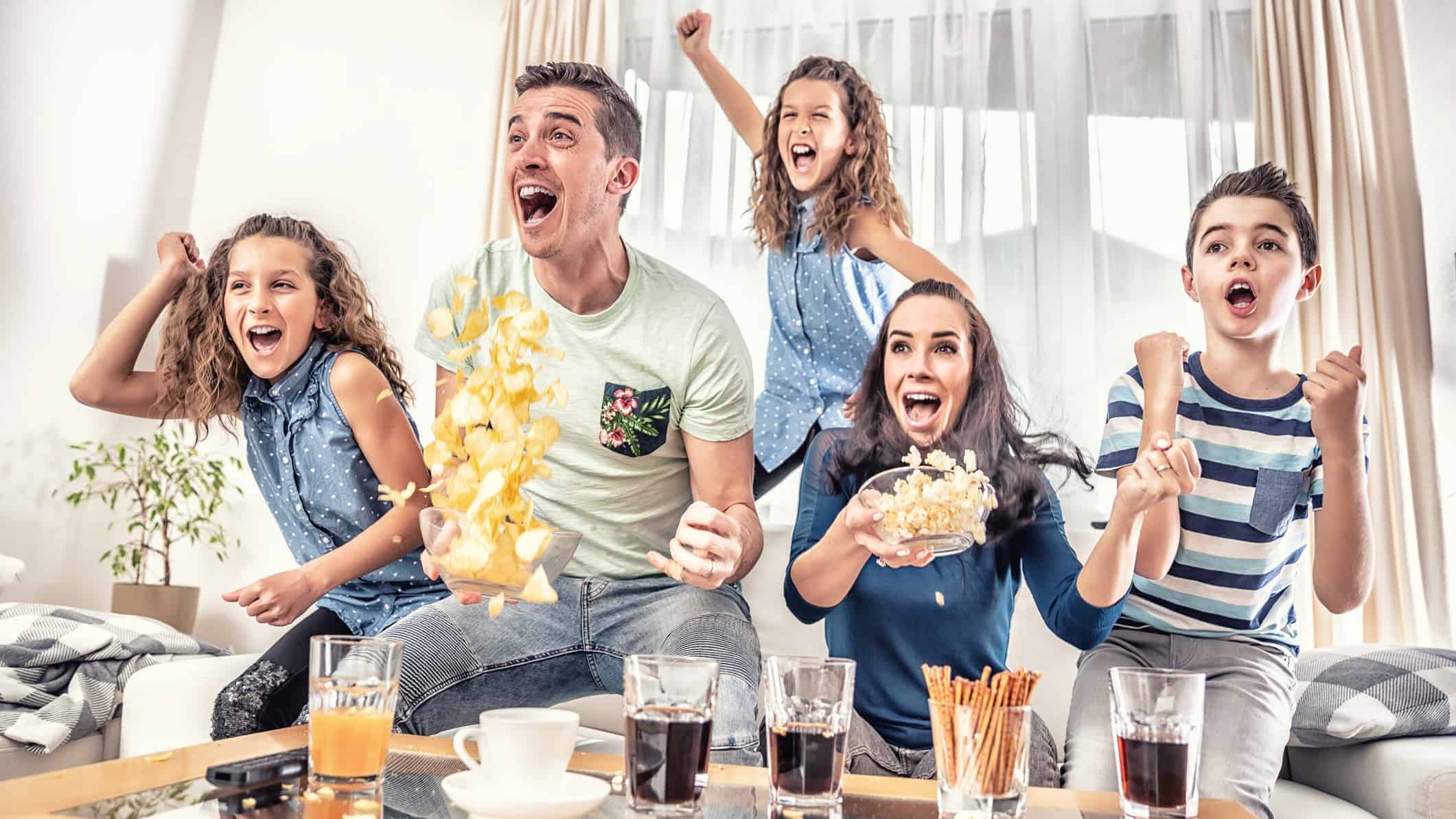 Family jumps up and cheers while watching TV.