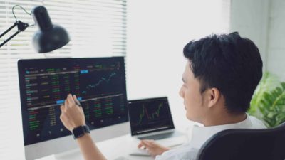 A share market analyst looks at his computer screen in front of him showing ASX share price movements