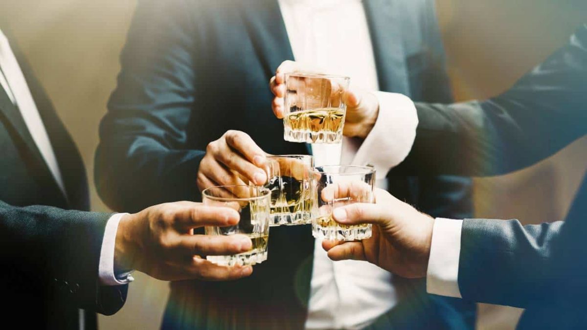 Three gentleman in suits clink their glasses of whiskey together in celebration of the rebounding Lark share price today