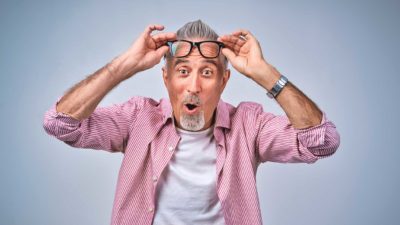 A man raises his reading glasses in a look of surprise.