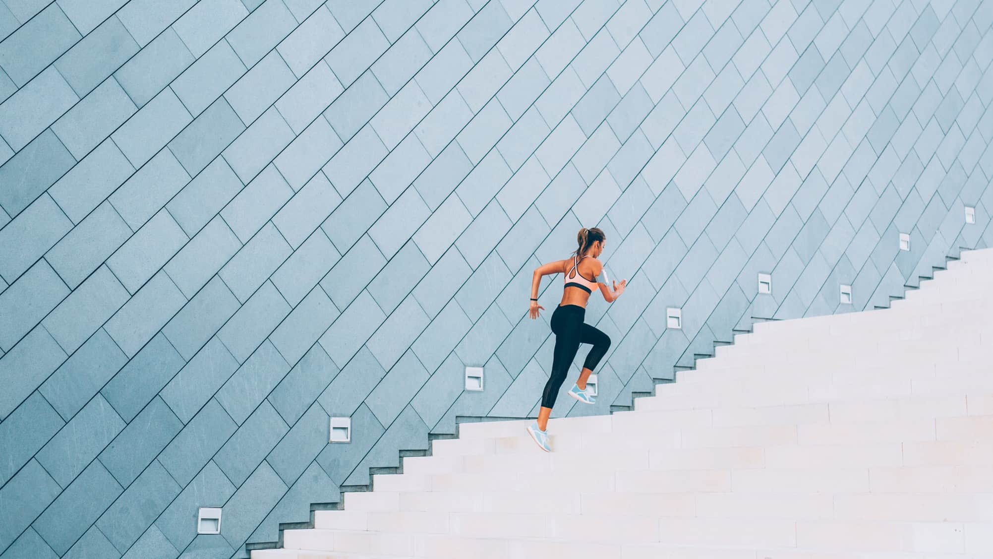 A female runner climbs a set of stairs, running with strength and pace.