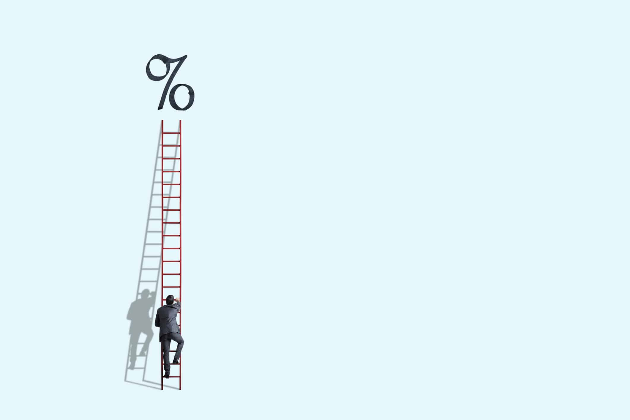 Man climbing ladder to percentage sign, symbolising higher interest rates.