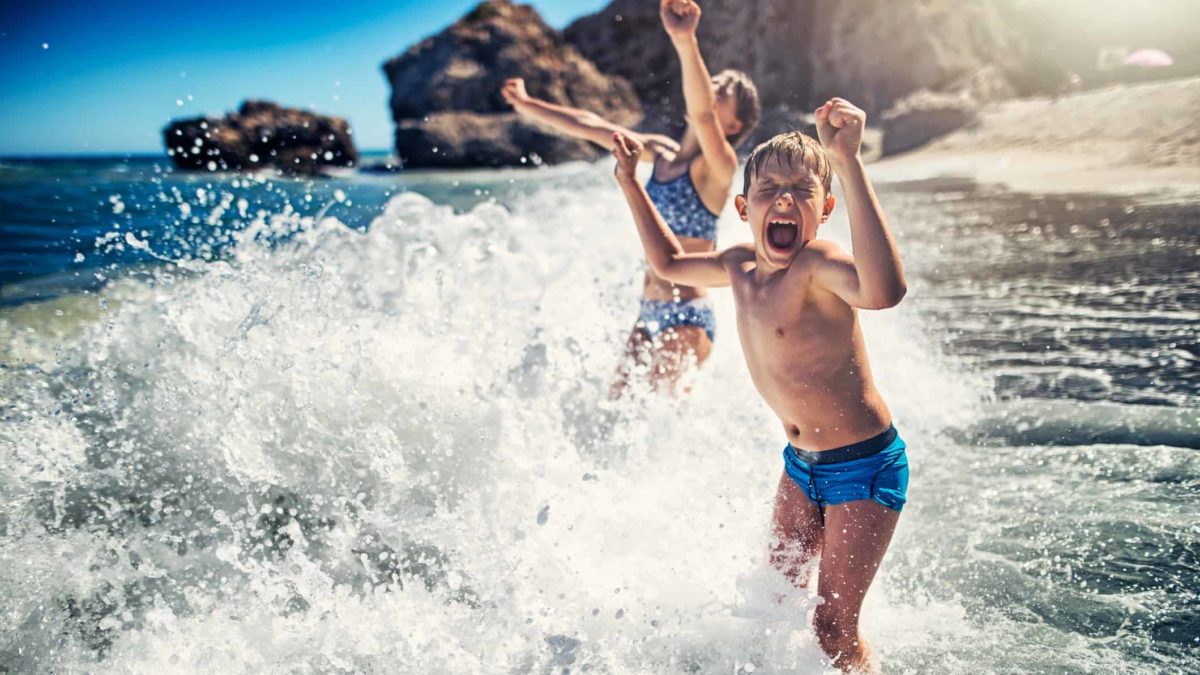 Two kids play joyfully in the crashing waves.