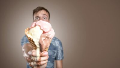 A man's eyes pop behind the ice cream melting in his hands, making a mess.