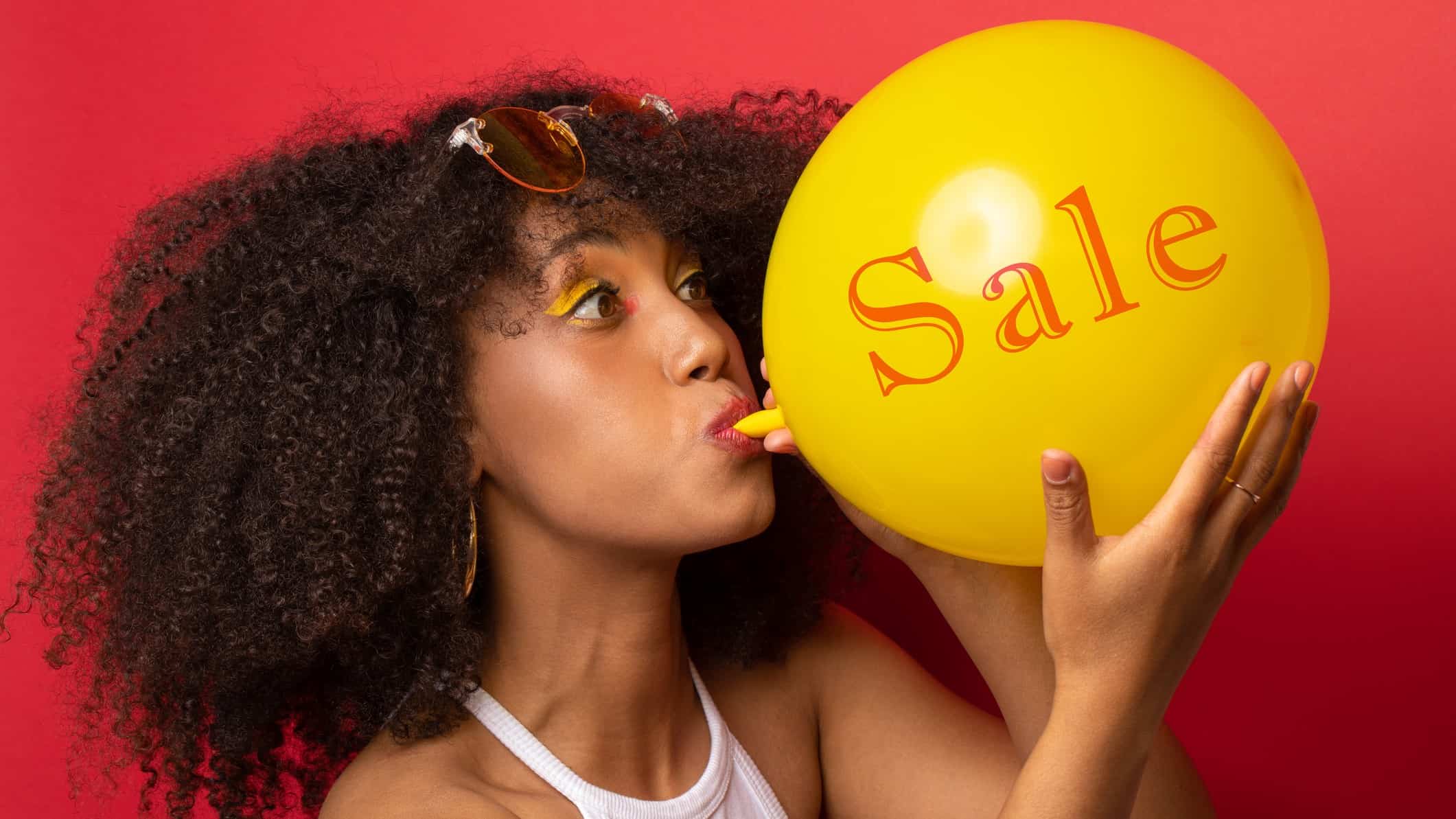 A woman inflates a balloon with the word 'sale' on it.