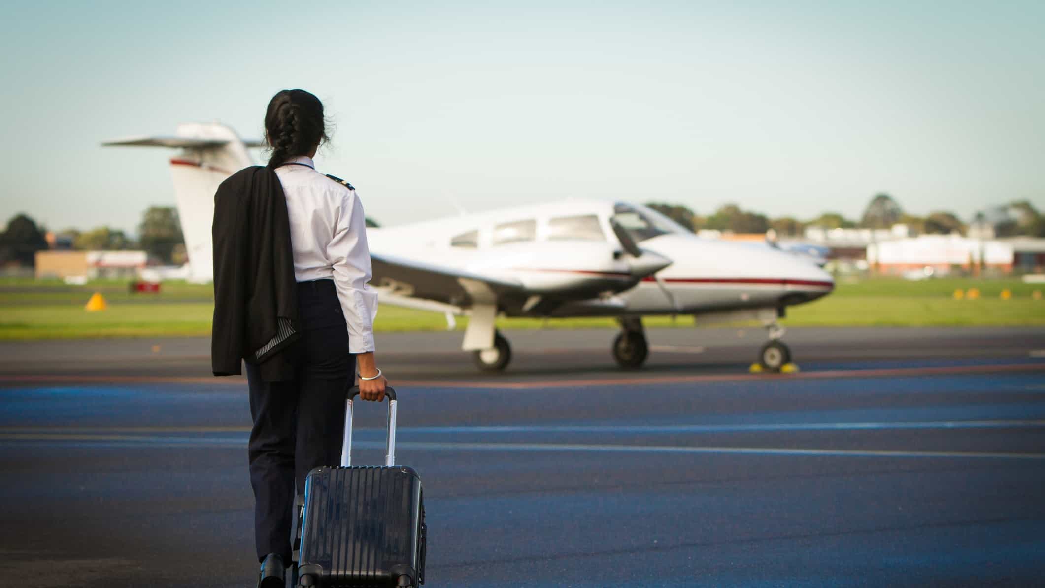 A female pilot strides across the tarmac to an aeroplane.