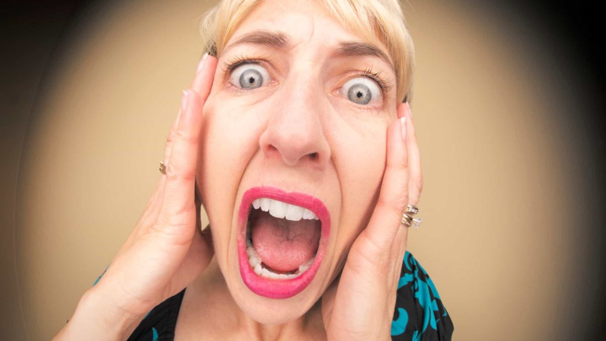 A woman holds her head and screams.
