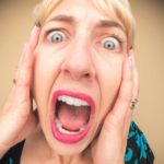 A woman holds her head and screams.