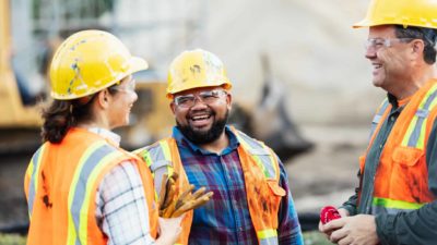 Three happy construction workers on an infrastructure site have a chat.