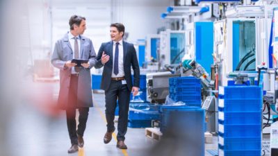 Two men discussing a deal as they walk through an electronics warehouse.