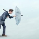 A person holds strong behind their umbrella as they weather the oncoming storm.