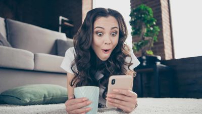 A woman is excited as she reads the latest rumour on her phone.