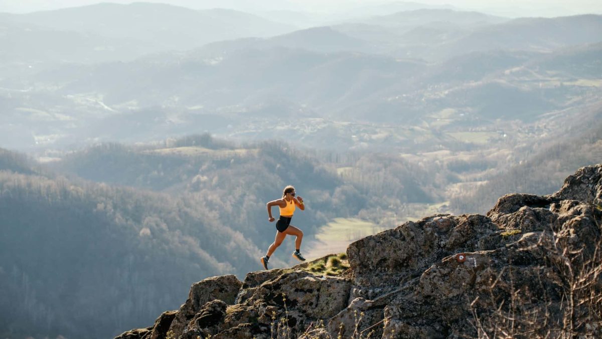 A woman charges up a steep hill in the mountain ranges.