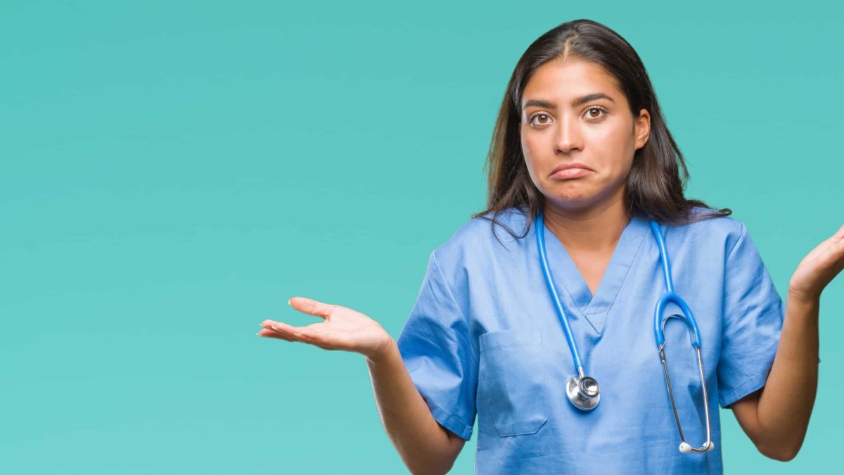 A health professional wearing a stethoscope and scrubs shrugs with uncertainty.