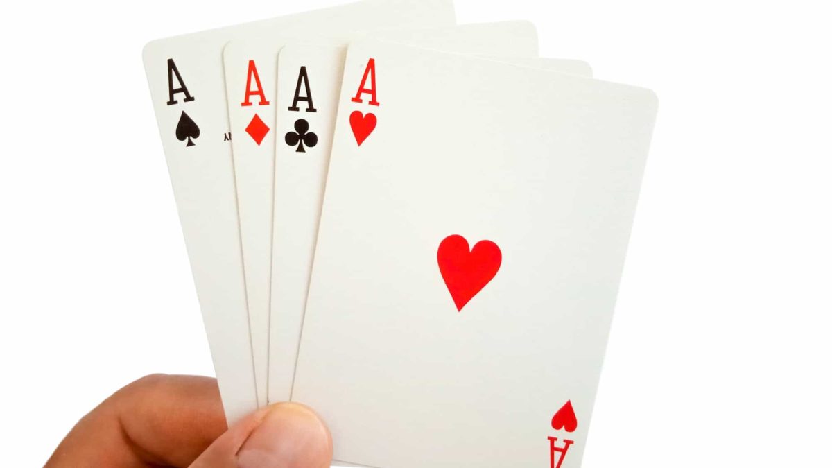 a close up picture of a hand holding four Ace cards - the aces of spades, diamonds, clubs and hearts.