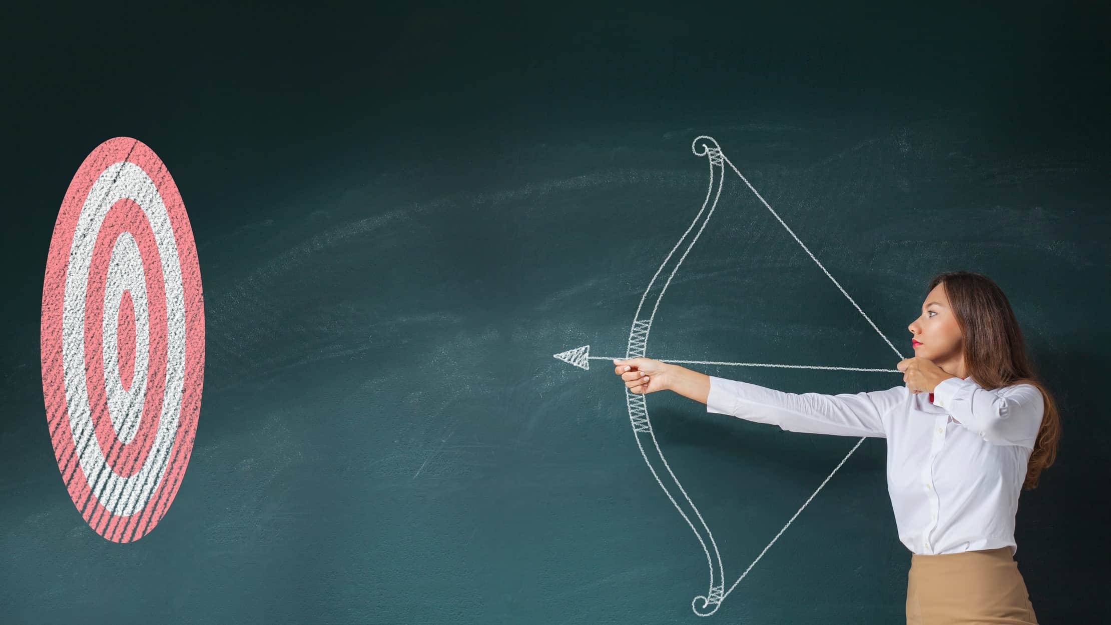 A businesswoman aims an arrow at a target