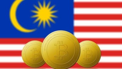 three large bitcoin tokens appear against the backdrop of a Malaysian flag.