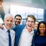 A group of business people pump the air and cheer.