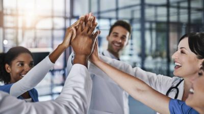 A group of people in a corporate setting do a collective high five.