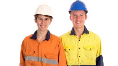 two young mining apprentices wearing their high visibility gear and hard hats stand together smiling.