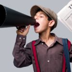 a newsboy wearing historical costume of peaked cap and braces yells into an old fashioned megaphone while holding a newspaper in one hand, a so-called newsboy of previous eras when newsboys sold newspapers on street corners.