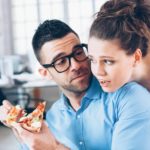 Young couple having pizza on lunch break at workplace.