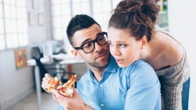 Young couple having pizza on lunch break at workplace.