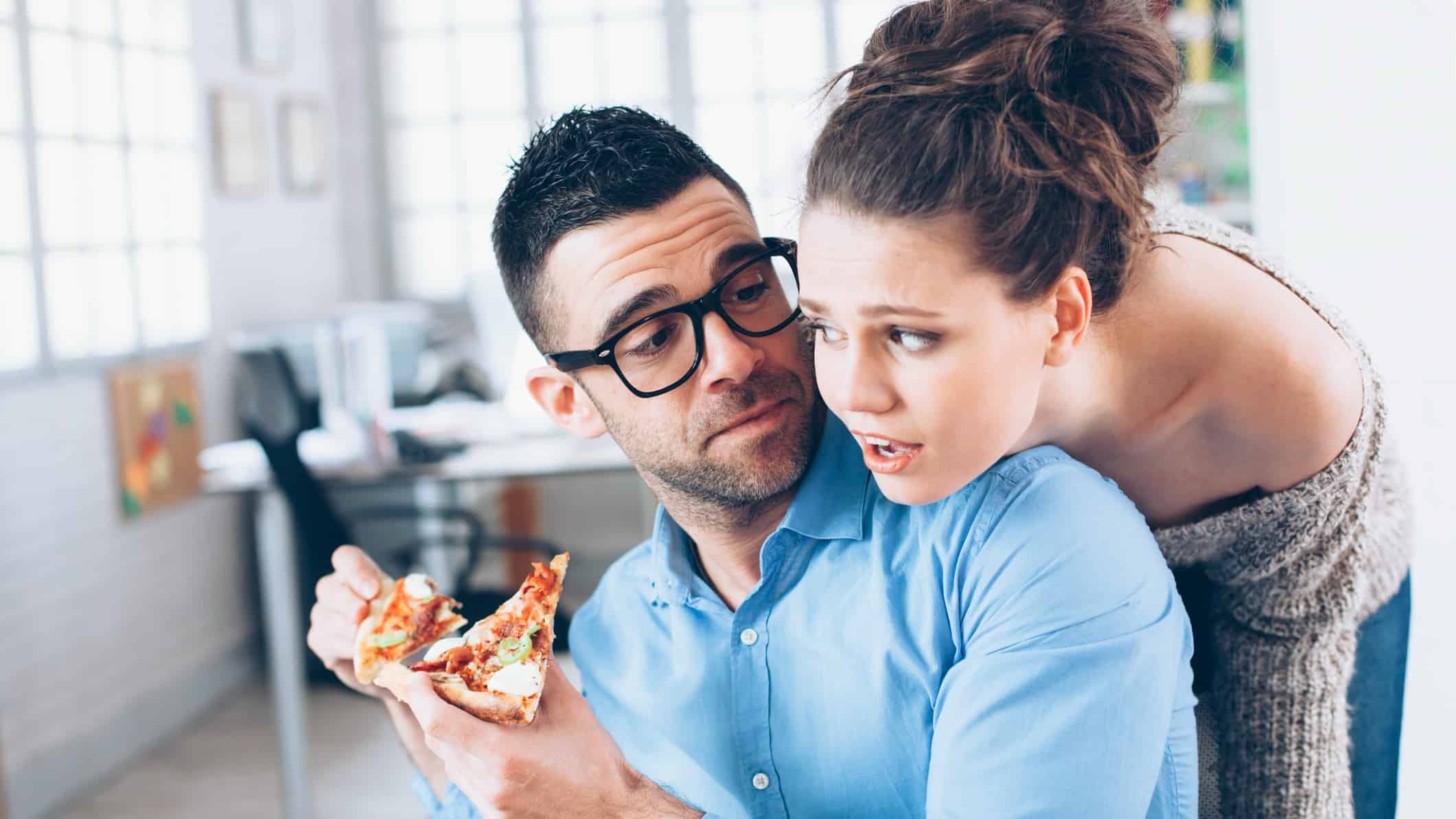 Young couple having pizza lunch break at workplace.
