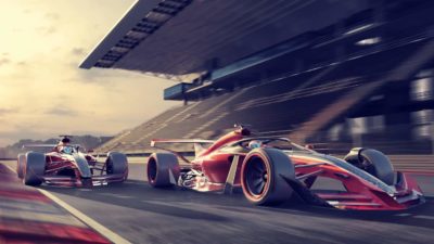 Two race cars on a track at sunset.