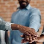 Three business people join hands in strength and unity