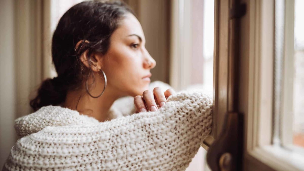 Sad woman with big earring looks out the window.