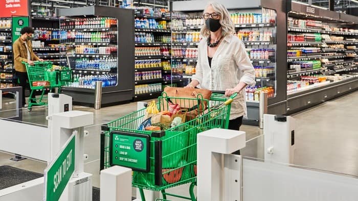 a shopper pushes a shopping trolley full of groceries through a scanning device in an Amazon store in the United States.