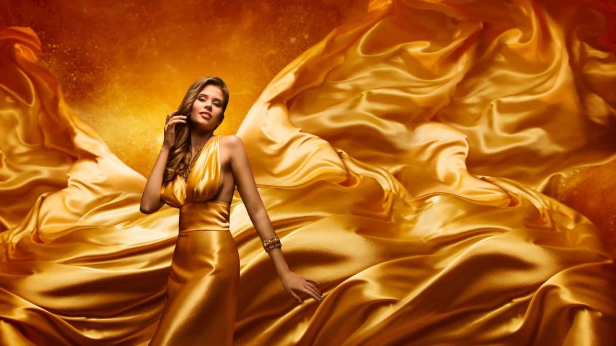 A woman in a flowing gold silk dress.