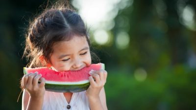 A little girl eats a juicy watermelon.