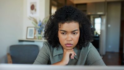 A young woman looks at something on her laptop, wondering what will come next.